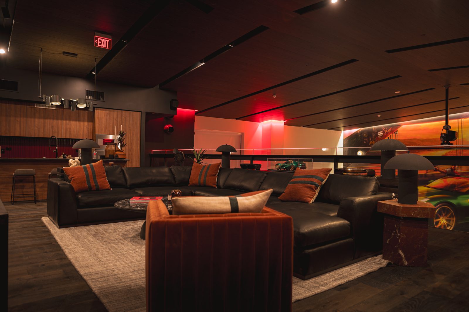 Lounge mezzanine of T11 Car Condo #303 at COTA with leather sectional, kitchen and red accent lighting